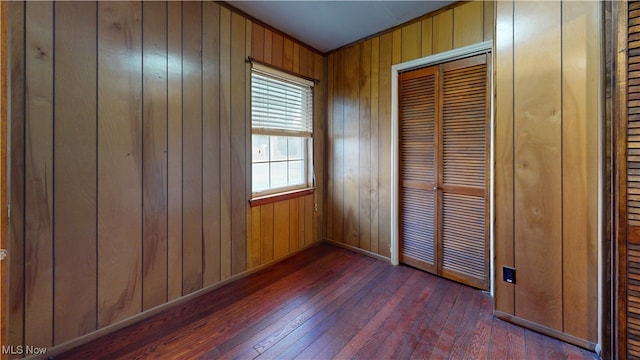 unfurnished bedroom with dark hardwood / wood-style floors and wooden walls