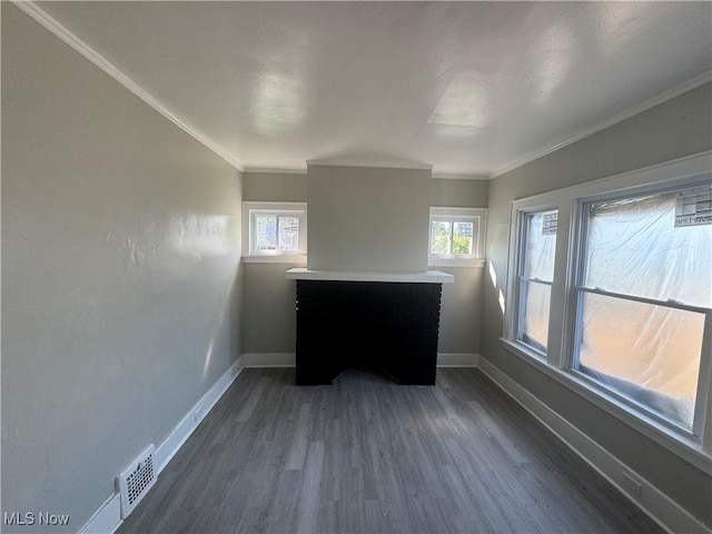 spare room with a healthy amount of sunlight, crown molding, and dark wood-type flooring