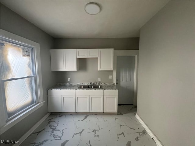 kitchen featuring white cabinetry, sink, and light stone countertops