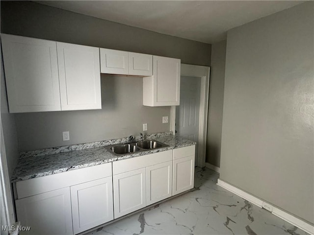 kitchen with white cabinetry, sink, and light stone counters