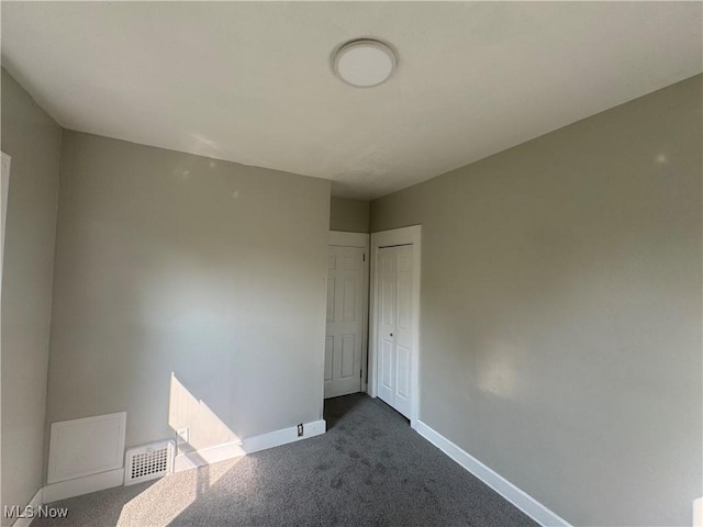 unfurnished room featuring dark colored carpet