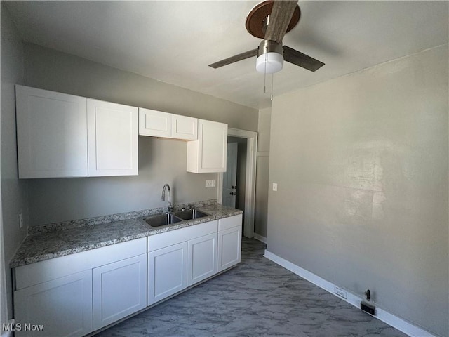 kitchen with ceiling fan, white cabinetry, and sink