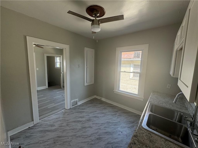 kitchen featuring white cabinetry, ceiling fan, and sink