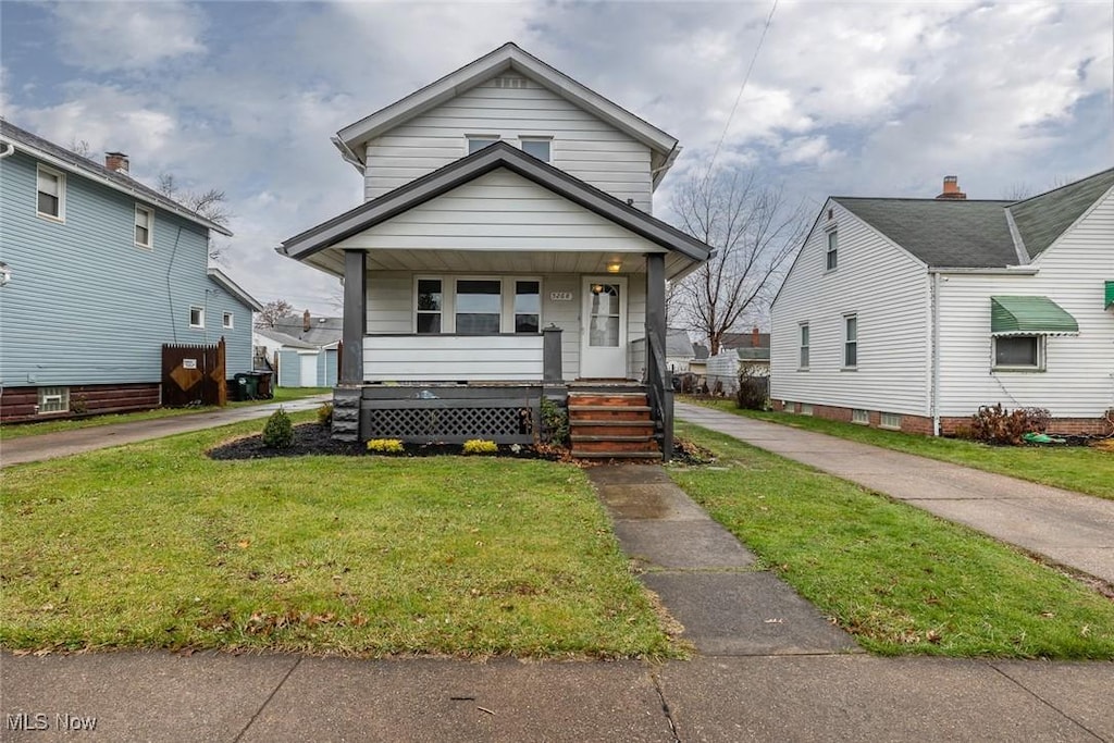 bungalow-style house featuring covered porch and a front yard