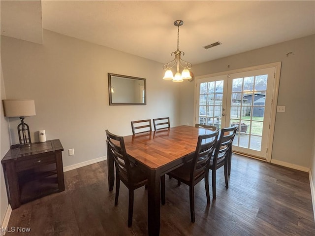 dining space with french doors, dark wood-type flooring, and a chandelier