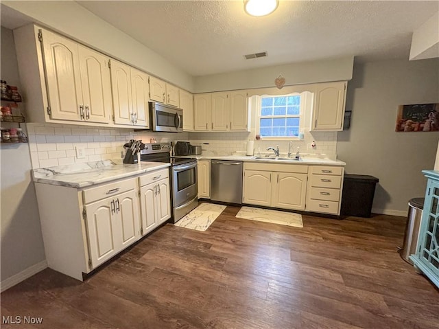 kitchen with dark wood-type flooring, sink, white cabinets, and stainless steel appliances