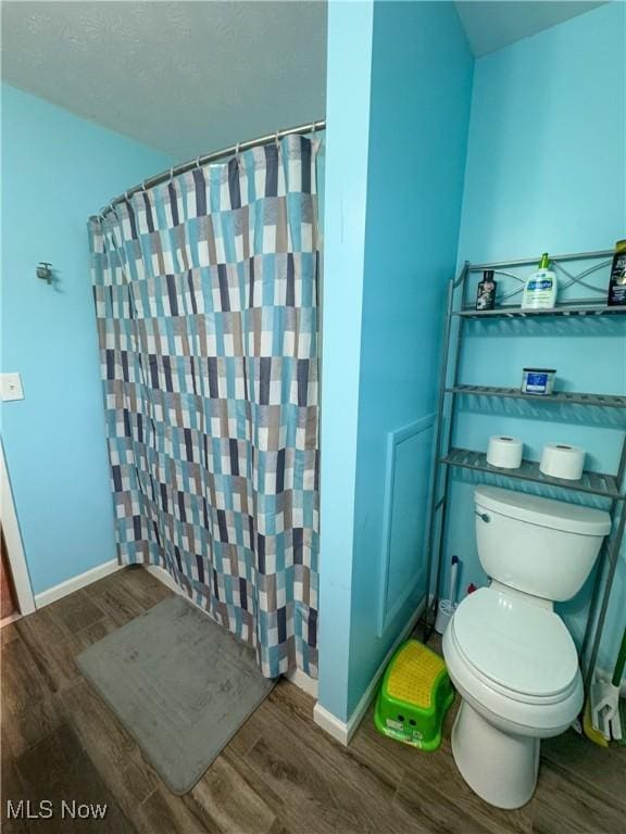 bathroom with a shower with shower curtain, wood-type flooring, and toilet