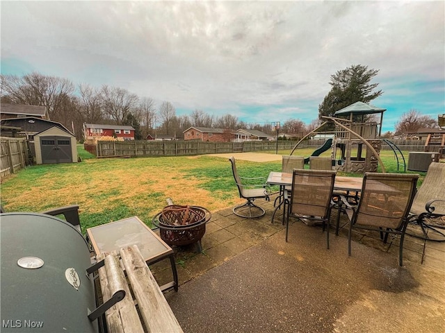 view of patio with a storage unit, a playground, and an outdoor fire pit