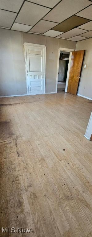 spare room with a paneled ceiling and light wood-type flooring