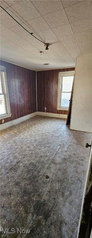 unfurnished room with a wealth of natural light and wooden walls