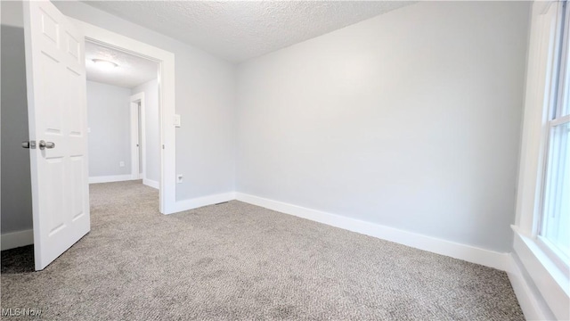 carpeted empty room featuring a textured ceiling