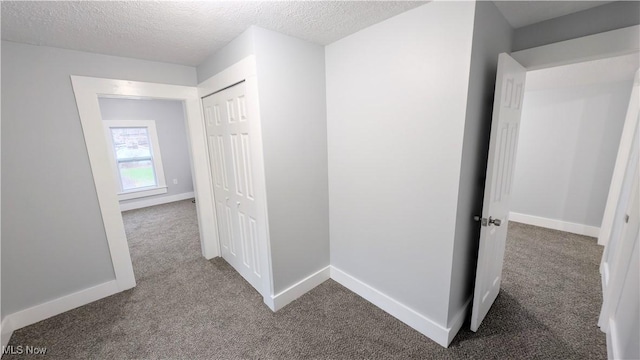 hallway featuring carpet flooring and a textured ceiling