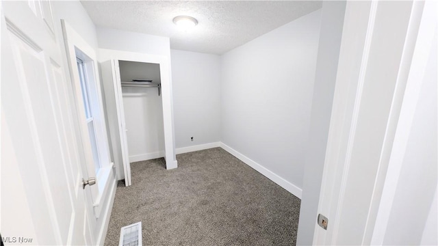 unfurnished bedroom with carpet, a textured ceiling, and a closet