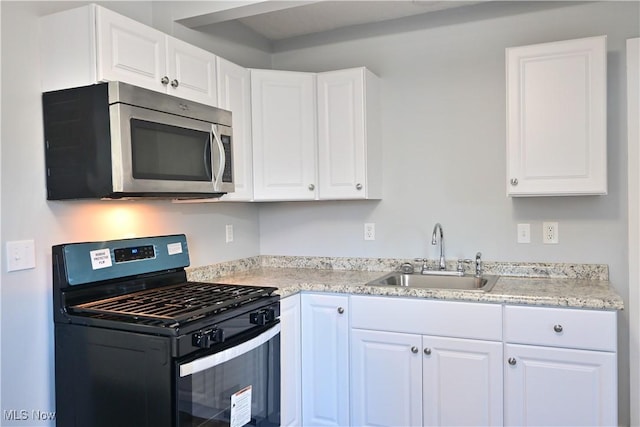 kitchen with white cabinets, gas stove, and sink