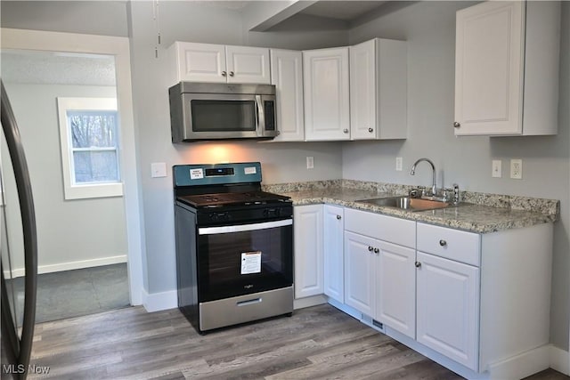 kitchen with white cabinetry, sink, appliances with stainless steel finishes, and light hardwood / wood-style flooring