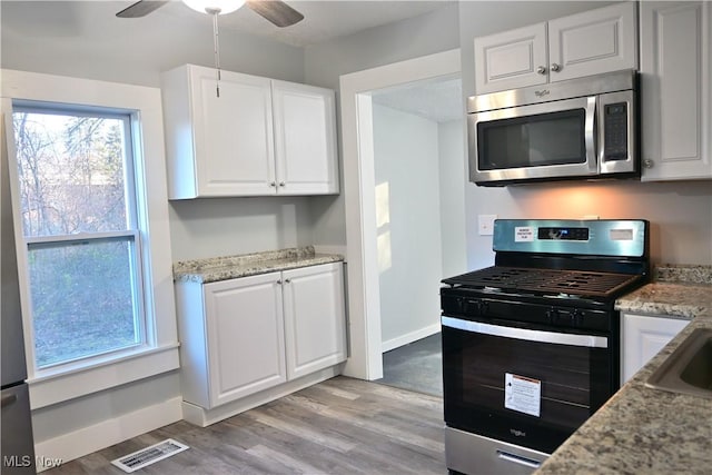 kitchen with light hardwood / wood-style flooring, ceiling fan, light stone countertops, white cabinetry, and stainless steel appliances