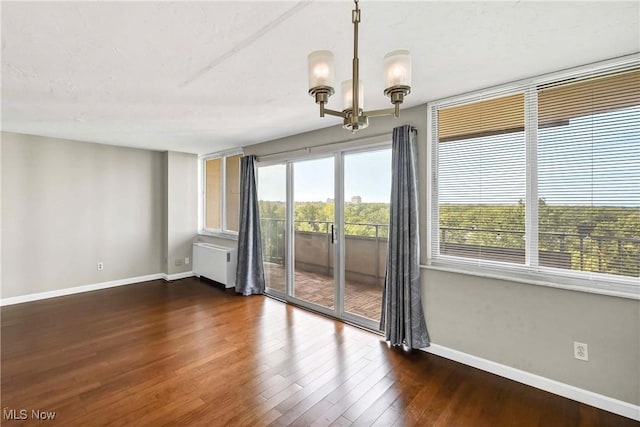 unfurnished room featuring a notable chandelier, dark wood-type flooring, and radiator