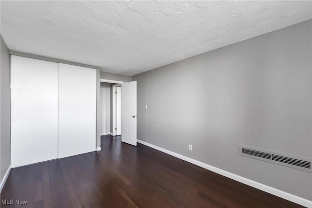 unfurnished bedroom featuring dark hardwood / wood-style flooring and a closet