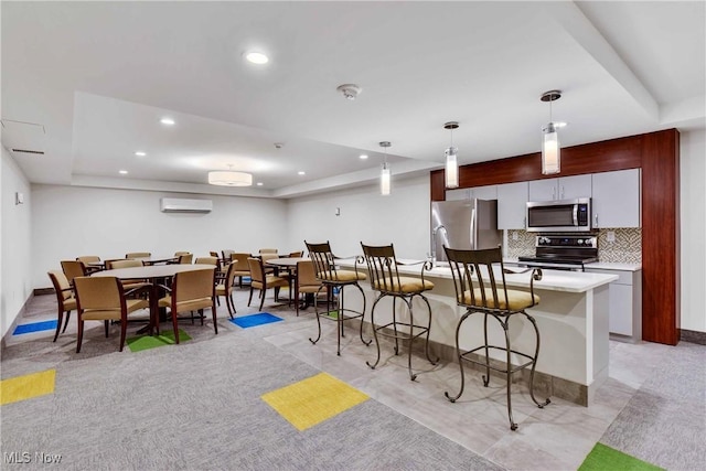 kitchen featuring a kitchen bar, appliances with stainless steel finishes, backsplash, pendant lighting, and a center island with sink