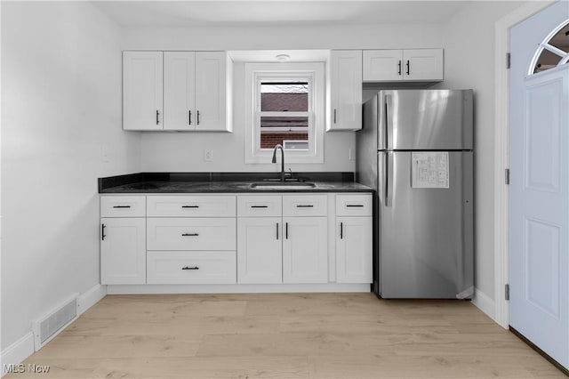 kitchen with stainless steel fridge, sink, and white cabinets