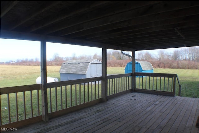 wooden deck featuring a storage unit, a rural view, and a yard