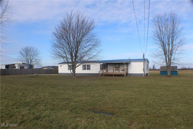 rear view of property with a yard, a deck, and a shed