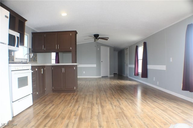 kitchen with white appliances, vaulted ceiling, ceiling fan, light wood-type flooring, and plenty of natural light