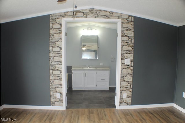 hallway with dark hardwood / wood-style flooring, lofted ceiling, and sink