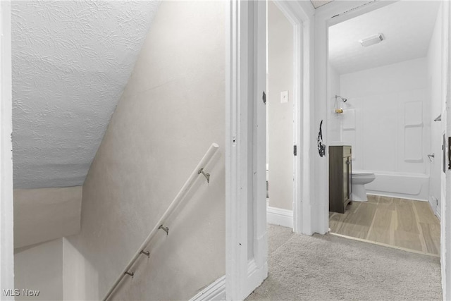 stairs with a textured ceiling and carpet floors