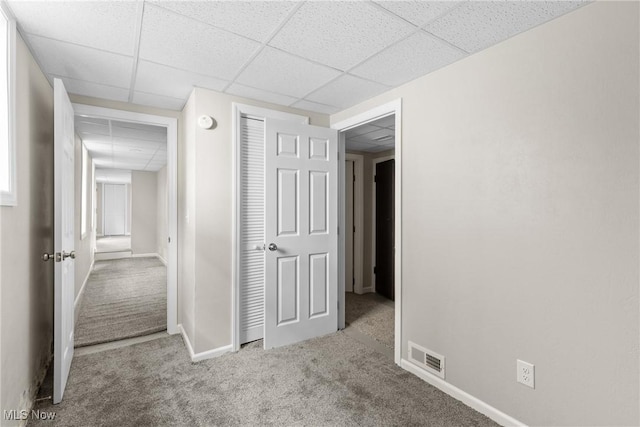 corridor featuring a drop ceiling and light colored carpet