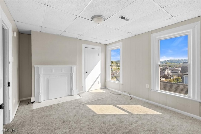 spare room featuring a paneled ceiling, light carpet, and a fireplace