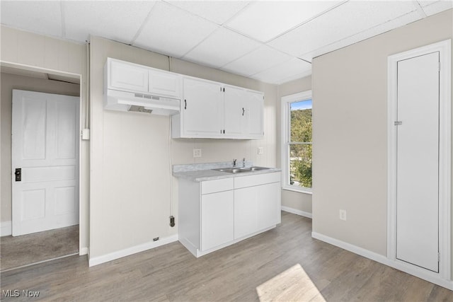 kitchen featuring a paneled ceiling, light hardwood / wood-style floors, white cabinetry, and sink