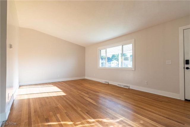 unfurnished room featuring hardwood / wood-style flooring and lofted ceiling