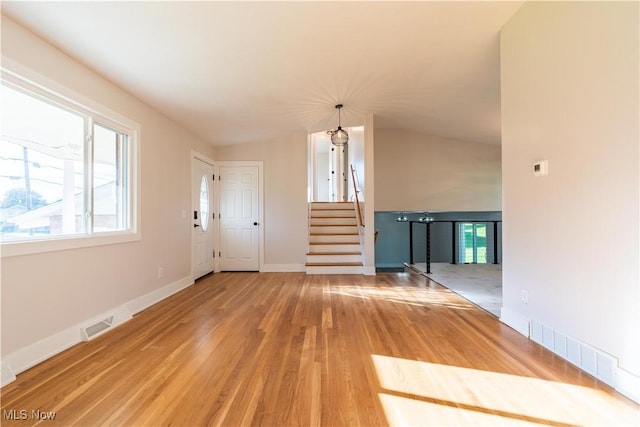 interior space featuring hardwood / wood-style floors, lofted ceiling, and an inviting chandelier