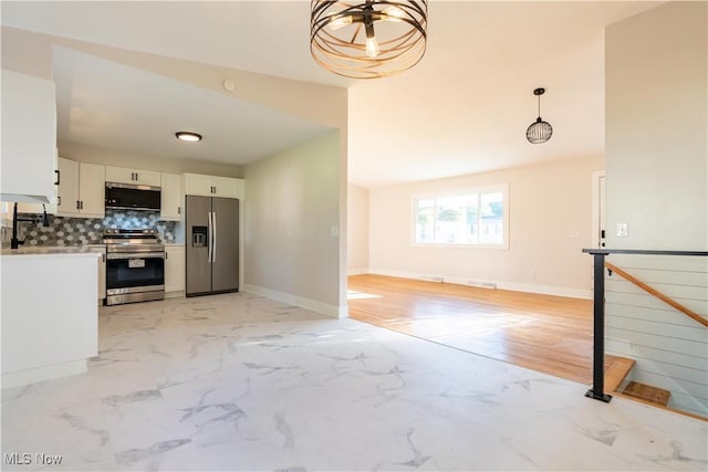 kitchen featuring hanging light fixtures, tasteful backsplash, lofted ceiling, white cabinets, and appliances with stainless steel finishes