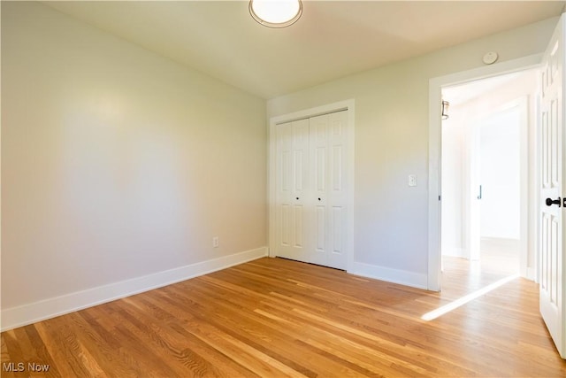 unfurnished bedroom with light wood-type flooring and a closet