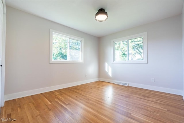 spare room featuring a wealth of natural light and light hardwood / wood-style floors