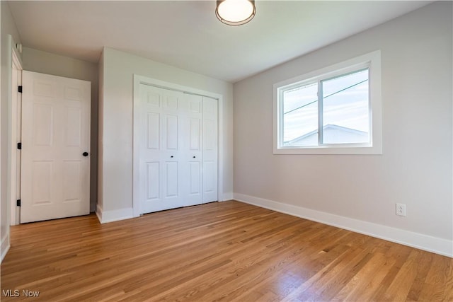 unfurnished bedroom featuring light hardwood / wood-style flooring and a closet