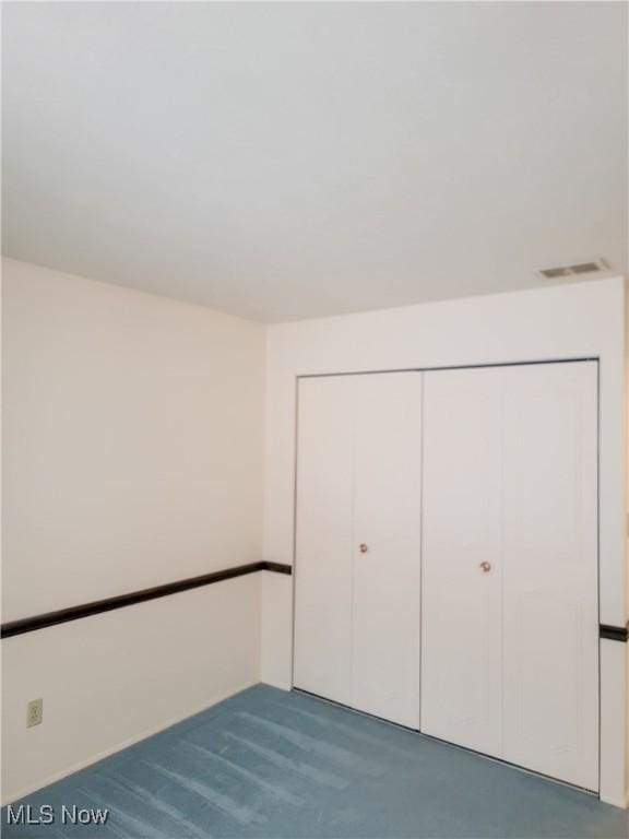 unfurnished bedroom featuring dark colored carpet and a closet