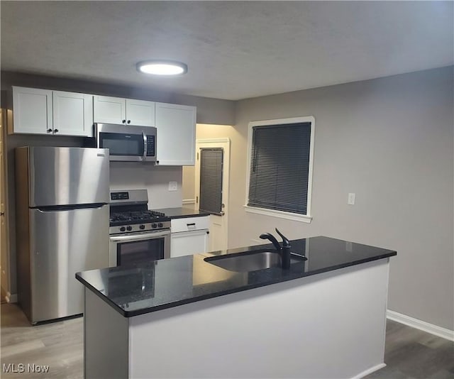 kitchen with sink, hardwood / wood-style flooring, white cabinetry, a kitchen island with sink, and stainless steel appliances