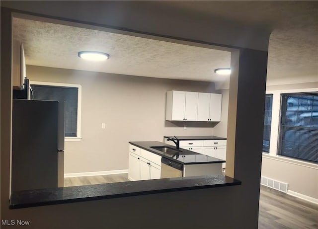 kitchen with paneled built in refrigerator, dishwasher, white cabinets, and kitchen peninsula