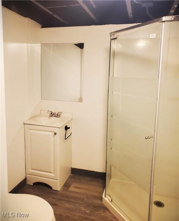 bathroom featuring vanity, toilet, a shower with shower door, and hardwood / wood-style floors