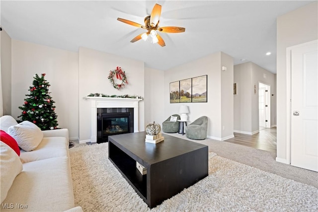 living room featuring carpet, ceiling fan, and a tiled fireplace