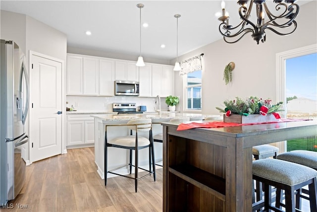 kitchen with white cabinetry, pendant lighting, an island with sink, and stainless steel appliances