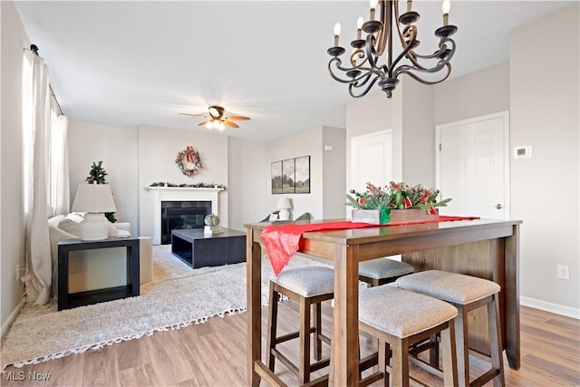 dining room featuring ceiling fan with notable chandelier and hardwood / wood-style flooring