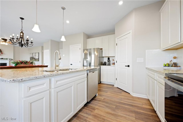 kitchen with backsplash, white cabinets, sink, an island with sink, and appliances with stainless steel finishes