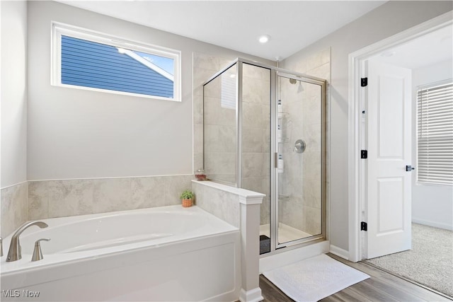 bathroom featuring wood-type flooring and shower with separate bathtub