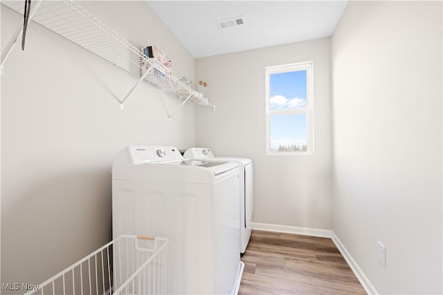 clothes washing area featuring light hardwood / wood-style flooring and washer and clothes dryer