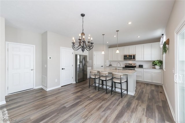 kitchen with a sink, pendant lighting, white cabinetry, an island with sink, and stainless steel appliances