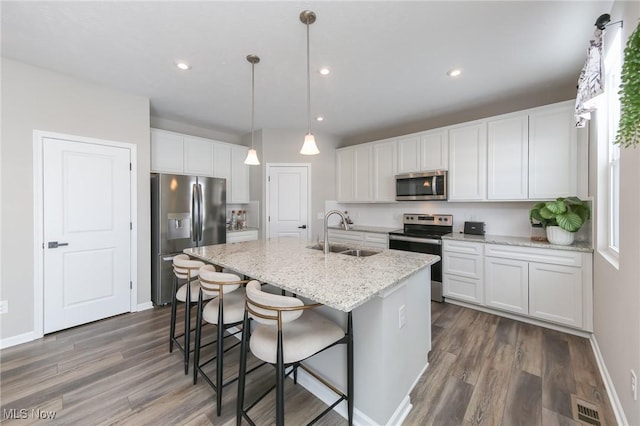 kitchen with light stone counters, white cabinetry, a sink, and appliances with stainless steel finishes